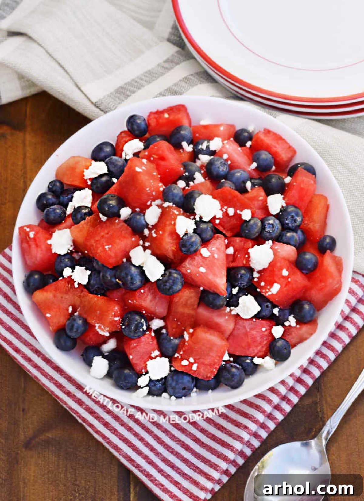 A beautiful watermelon feta salad with blueberries in a white serving bowl, ready to be enjoyed on a sunny day.