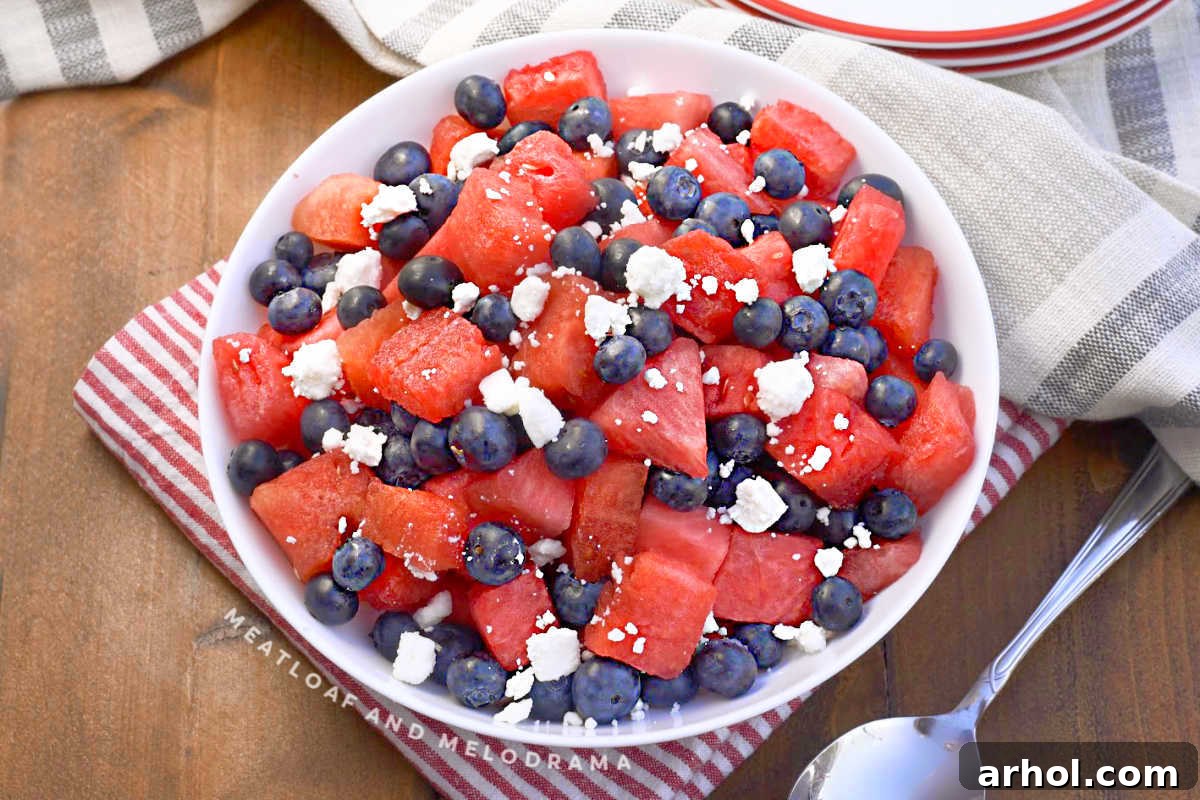Close-up of watermelon, feta, and blueberry salad in a white serving bowl, showing the fresh ingredients.