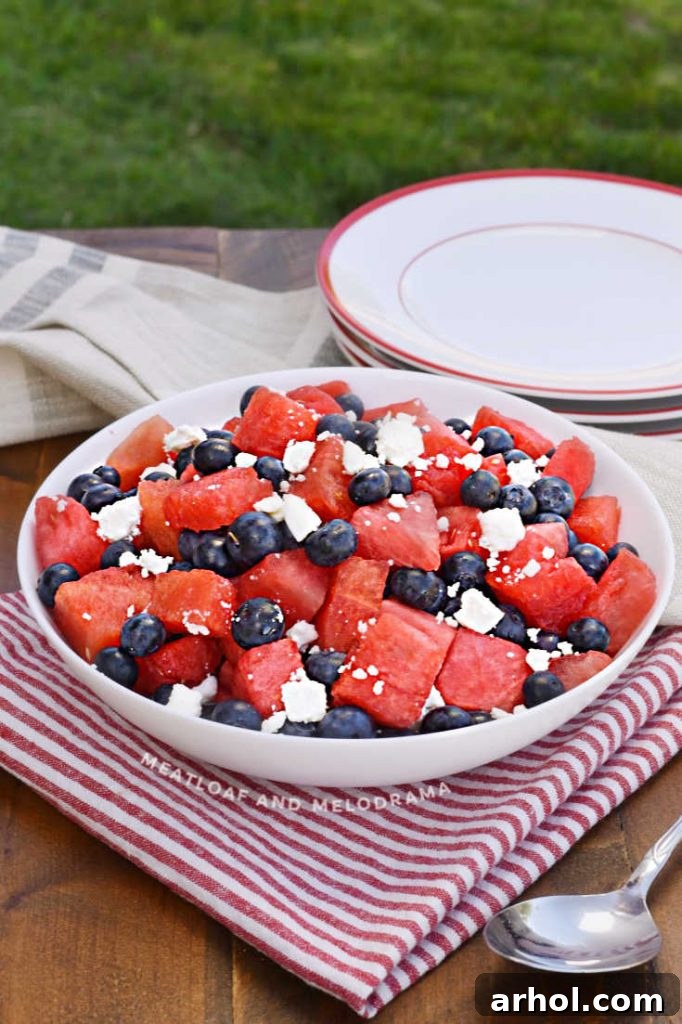 A large bowl of colorful watermelon, feta cheese, and blueberries, artfully arranged on an outdoor table.