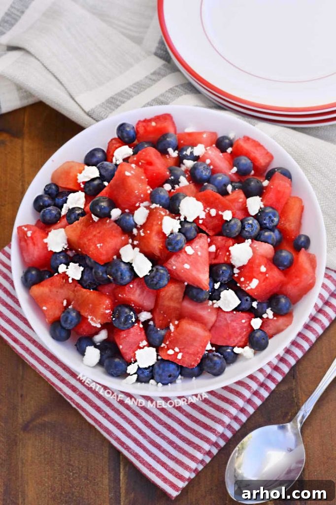 A visually appealing bowl of cut-up watermelon, vibrant blueberries, and crumbled feta cheese, sitting enticingly on a wooden table.