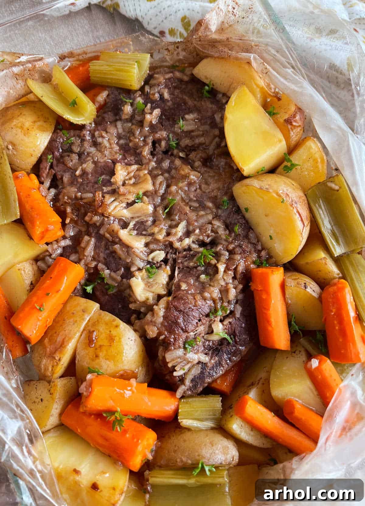 A succulent beef pot roast cooked in an oven bag, surrounded by perfectly tender potatoes, carrots, and celery.