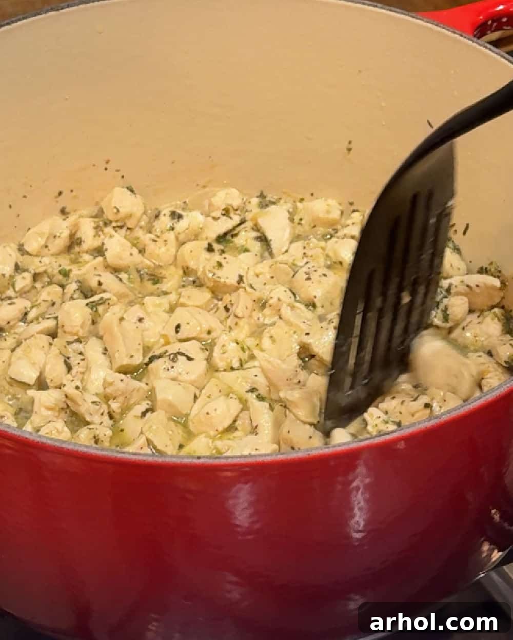 Close-up of diced chicken pieces browning in a Dutch oven.