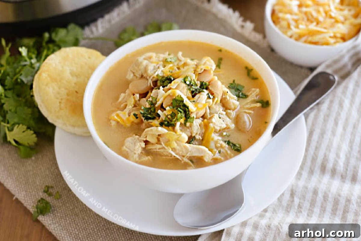 bowl of instant pot white chicken chili with white beans, corn and cheese and cilantro