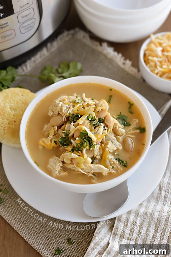 Instant Pot white chicken chili with white beans, corn and cheese in a white bowl with cilantro