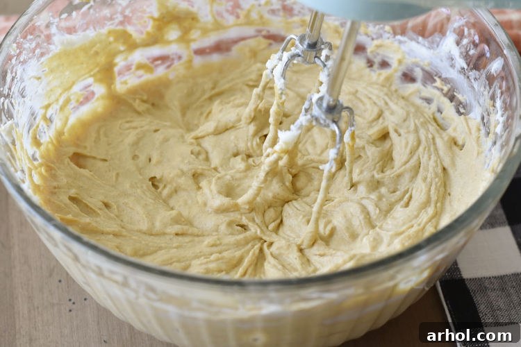 Velvety Instant Pot Pumpkin Cheesecake 4 Rich and creamy pumpkin cheesecake filling being mixed in a large bowl with an electric mixer, ready to be poured into the crust.