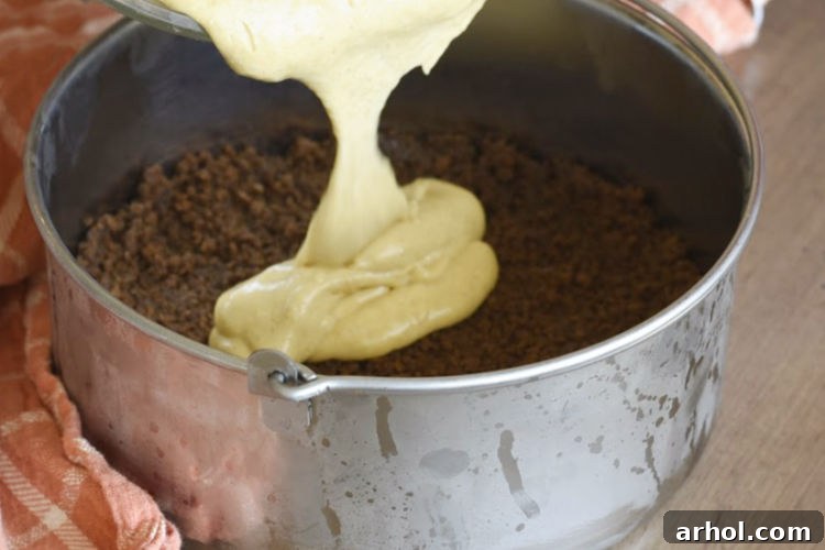 Velvety Instant Pot Pumpkin Cheesecake 5 Pouring the pumpkin cheesecake filling over the prepared gingersnap crust in a 7-inch springform pan before pressure cooking.