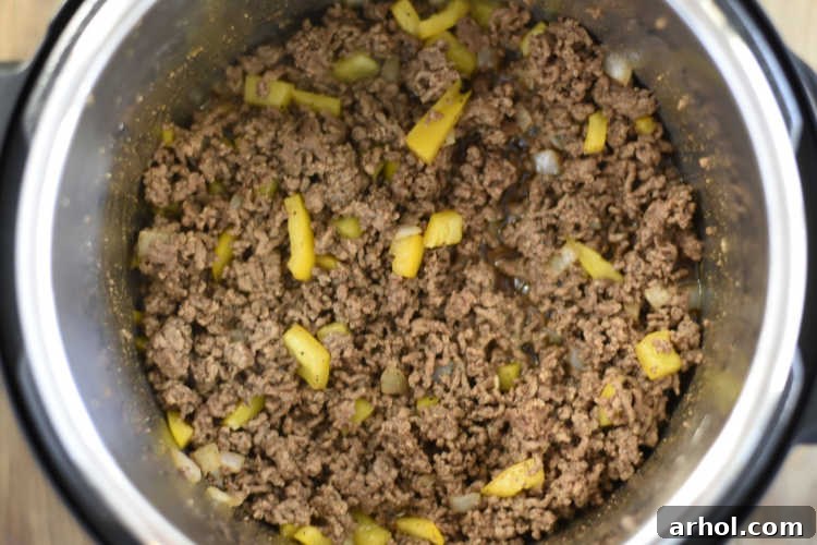 Sautéed ground beef and chopped yellow peppers cooking in the Instant Pot pressure cooker.