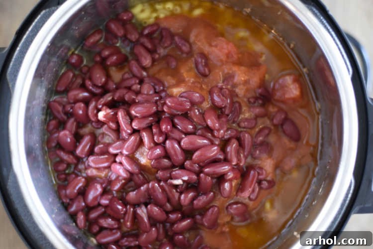All ingredients for chili mac with beans layered in the Instant Pot pressure cooker before cooking.