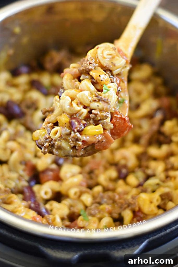 Close-up of creamy chili mac and cheese on a wooden spoon in the Instant Pot.
