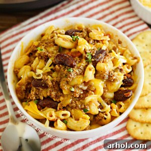 Instant Pot Chili Mac served in a white bowl with crackers on a wooden table, invitingly warm and comforting.