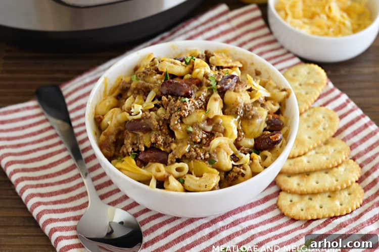A bowl of Instant Pot Chili Mac with beans and cheese, served with butter crackers on the side.
