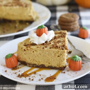 instant pot pumpkin cheesecake with gingerbread crust on a white plate with whipped cream, caramel and marshmallow pumpkins