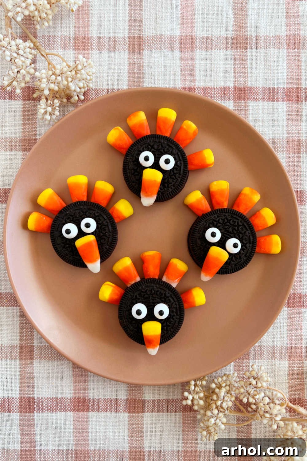 Oreo turkey cookies with Oreos and candy corn arranged on a festive Thanksgiving table, surrounded by fall decorations.