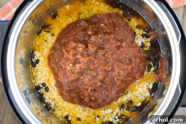 Salsa layered over rice, black beans and ground beef in the pressure cooker