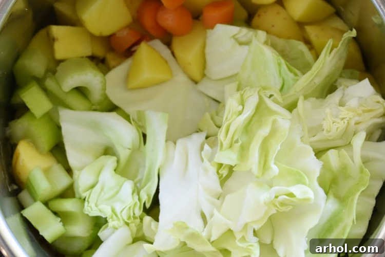 An Instant Pot filled to the brim with raw cabbage, celery, potatoes, and carrots, ready for pressure cooking.
