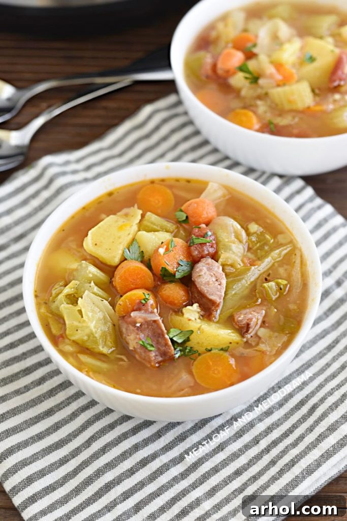 A beautiful white bowl filled with Instant Pot Kielbasa Cabbage Soup, garnished with fresh parsley.