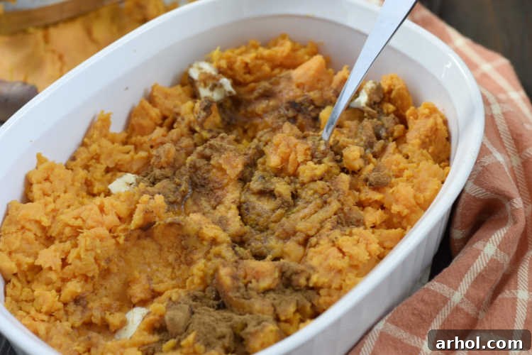 Mixing mashed sweet potatoes with rich butter and sweet brown sugar in a bowl, creating a flavorful base for the casserole.