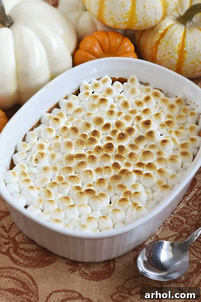A beautifully baked sweet potato casserole generously topped with fluffy, golden-brown marshmallows in a pristine white baking dish, ready for serving.