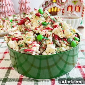 Christmas crunch snack mix with popcorn and pretzels on the table, garnished with festive candies.
