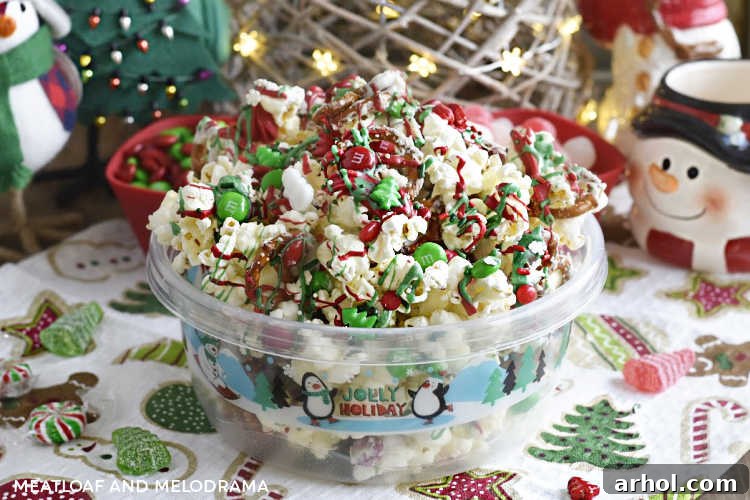 Christmas crunch snack mix with popcorn, pretzels, and an assortment of holiday candies presented beautifully in a festive holiday container, ready for sharing or gifting.