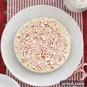 peppermint cheesecake topped with crushed candy canes on a white plate
