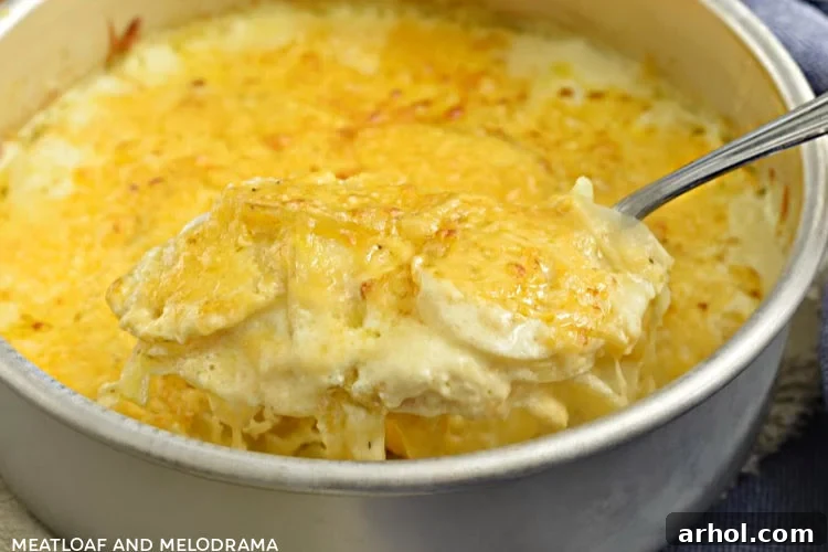 Instant Pot Potatoes Au Gratin on a serving spoon, showcasing the crisp cheese topping and tender layers