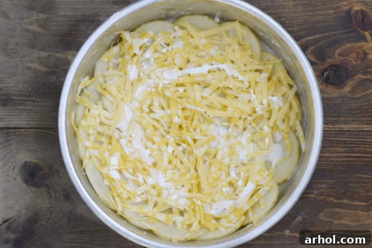Layers of thinly sliced potatoes, heavy cream, and shredded cheese in a round baking dish