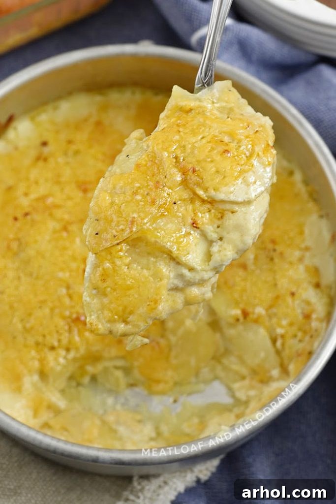 A serving spoon lifting a portion of Instant Pot Potatoes Au Gratin, showing layered potatoes and melted cheese