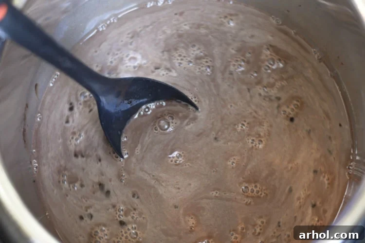 Velvety Smooth Instant Pot Hot Chocolate 4 Mixing cream and cocoa in the Instant Pot, creating a smooth and luscious hot chocolate mixture.