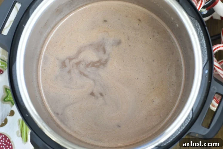 Velvety Smooth Instant Pot Hot Chocolate 5 Rich, warm hot chocolate steams in the Instant Pot, ready to be served to guests.