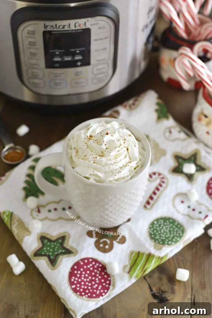 Velvety Smooth Instant Pot Hot Chocolate 6 Homemade hot cocoa in a white mug topped with generous whipped cream, garnished with a sprinkle of cocoa.