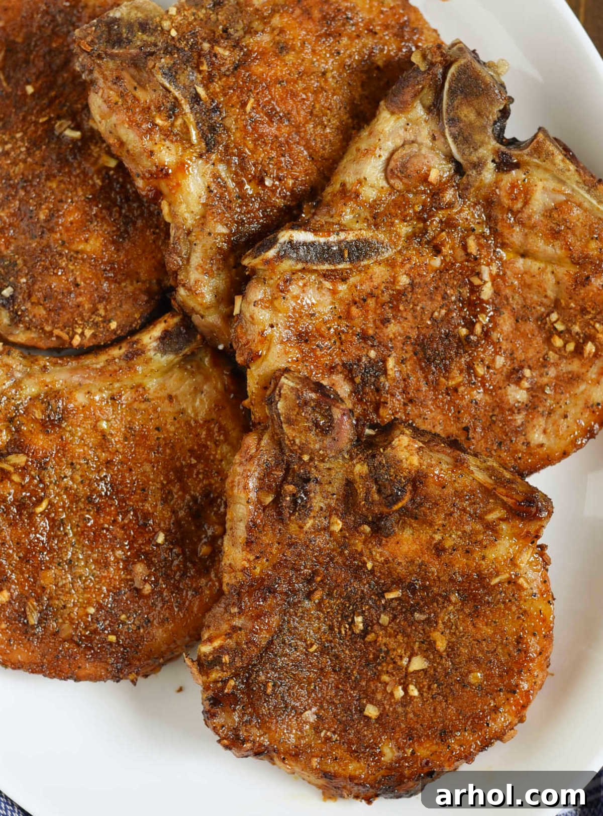 Platter of golden-brown air-fried pork chops, garnished with fresh herbs, showcasing their tender and juicy texture.