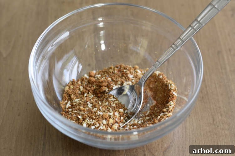 Various dry rub ingredients, including sea salt, garlic powder, smoked paprika, brown sugar, dried minced onions, pepper, and ancho chili powder, perfectly measured in small glass bowls.