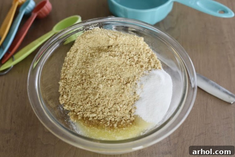 Graham cracker crumbs, sugar, and melted butter perfectly combined in a mixing bowl for the cheesecake crust.