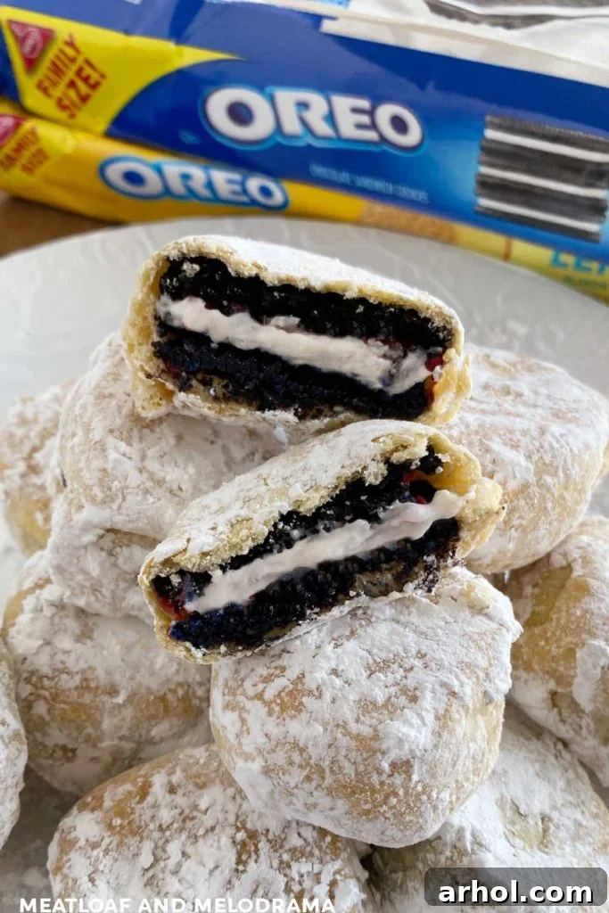 Golden brown air fryer fried Oreos coated in powdered sugar, stacked artfully on a white plate, ready to be served.