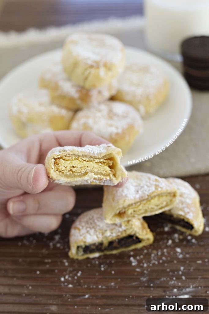 A hand gently holds a perfectly sliced air-fried lemon Oreo, clearly revealing its warm, tangy filling and the enticing crispy, golden-brown dough. A truly tempting sight.