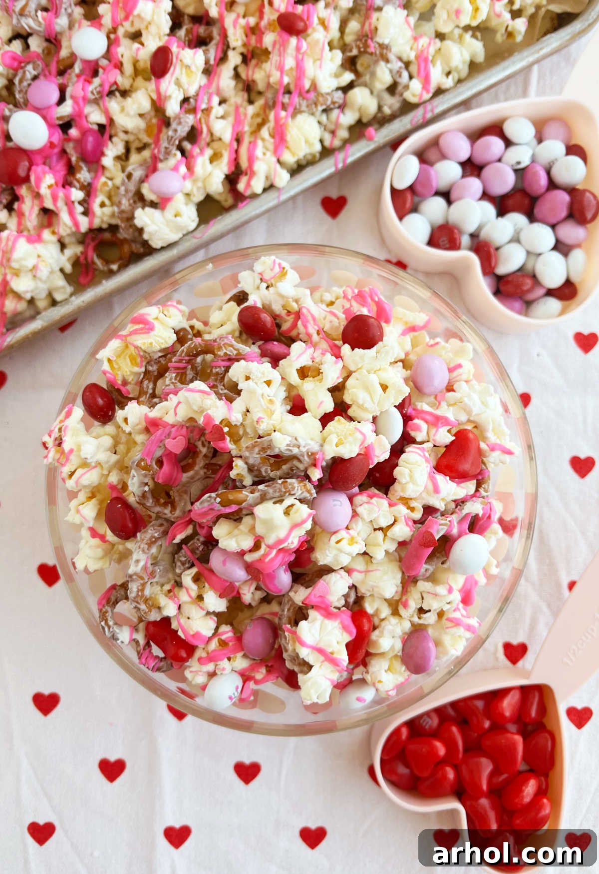 Sweetheart Snack Medley 2 A beautifully arranged Valentine's Day snack mix featuring popcorn, pretzels, and an assortment of red, pink, and white candies on a decorative table.
