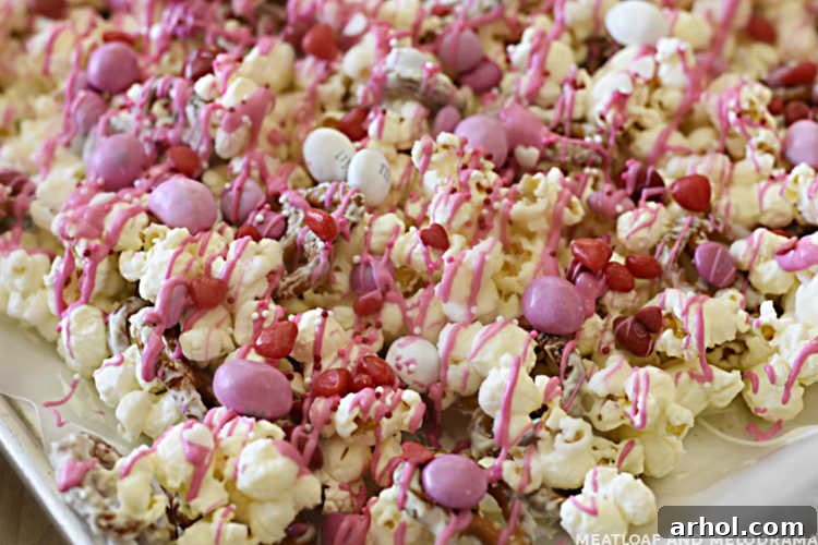 Sweetheart Snack Medley 6 A baking sheet showcasing the finished Valentine's Day snack mix, brimming with colorful M&M's and delicate pink candy coating drizzles.
