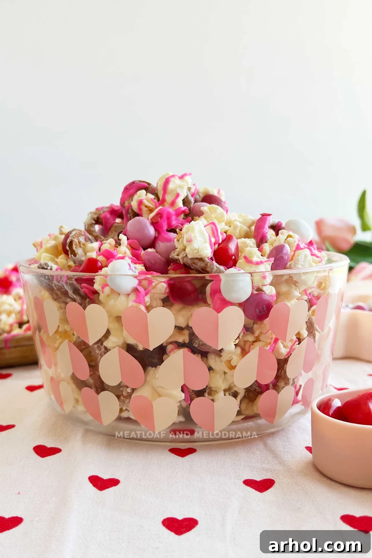 Sweetheart Snack Medley 8 A charming glass dish filled with Valentine's Day popcorn snack mix, decorated with heart motifs, showcasing the festive colors and textures.