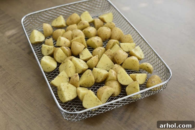 Seasoned and cubed baby potatoes ready to be air-fried, showing uniform cuts and a light coating of spices for optimal crisping.