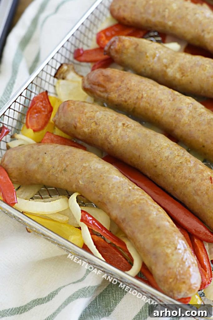 cooked italian sausage links with onions and bell pepper strips in metal omni plus air fryer tray