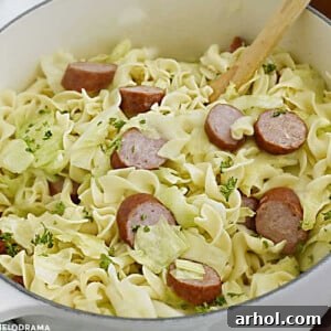 Haluski and kielbasa, fried cabbage with noodles and smoked sausage in a white Dutch oven