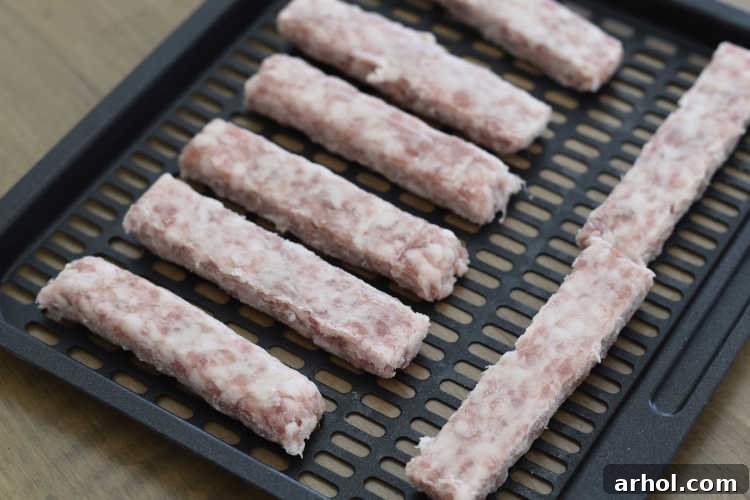 Raw uncooked breakfast sausage links laid out neatly on an Instant Pot Vortex Plus air fryer tray before cooking.