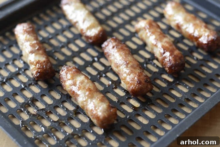 Perfectly cooked breakfast sausage links on an air fryer tray, showcasing their golden-brown color.