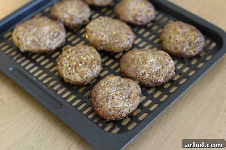 Golden-brown, perfectly cooked breakfast sausage patties resting on an air fryer tray.