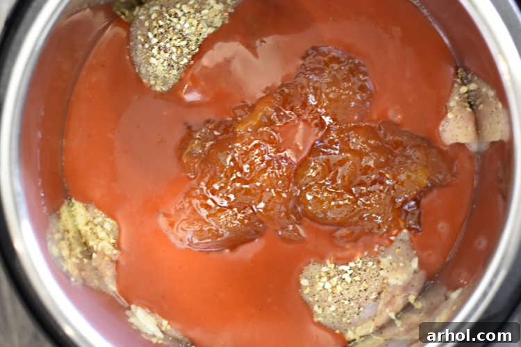Chicken breasts covered in apricot jam and Catalina dressing inside an Instant Pot pressure cooker before cooking.