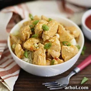instant pot orange chicken in a white bowl over rice with scallions