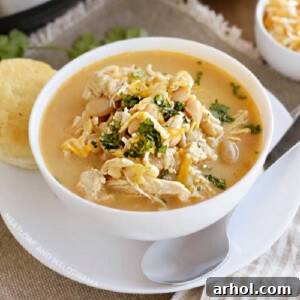 bowl of instant pot white chicken chili with white beans, corn and cheese and cilantro