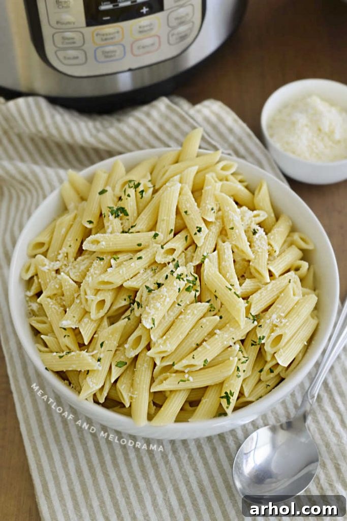 A bowl of penne pasta with Parmesan cheese next to an Instant Pot, showcasing a simple and delicious meal.