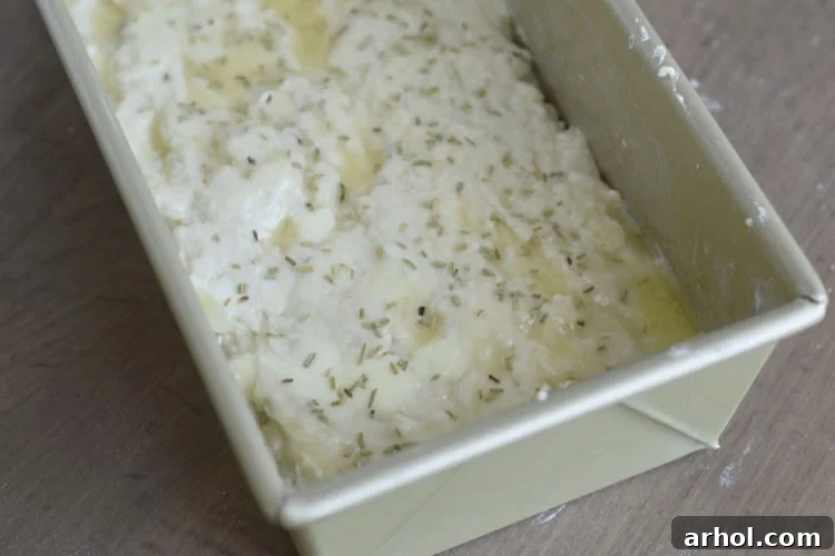 beer bread dough with rosemary on top in loaf pan